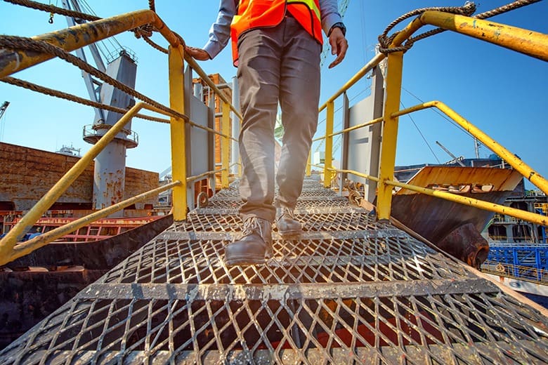 legs of worker or engineering wearing Safety shoes walking in mind step on the steel gangway bridge cross over at workplace, working in high stage and high level of insurance"r