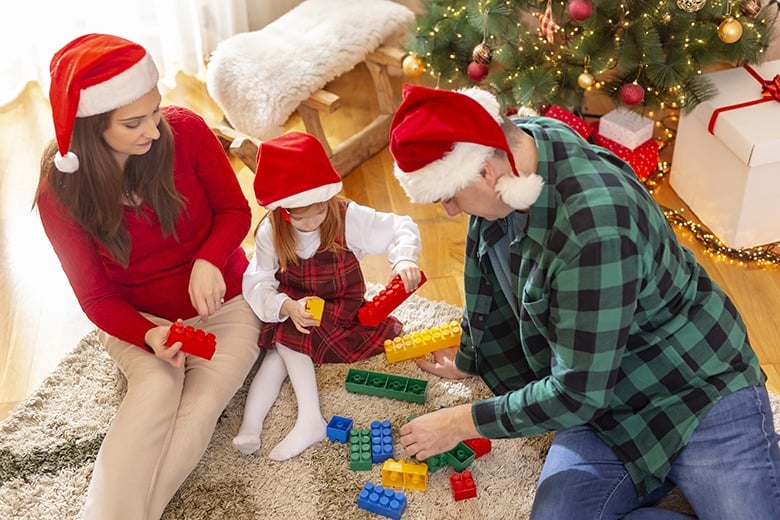 High angle view of parents sitting by the Christmas tree and playing with their child while celebrating Christmas at home