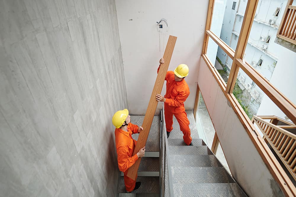 Workers carrying wood up the stairs